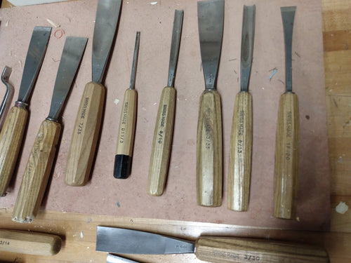 Wood carving gouges and chisels on a workbench